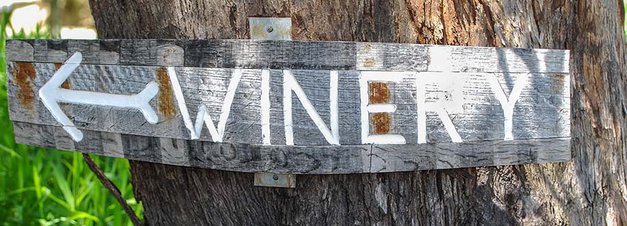 Winery sign painted on wine barrel staves and nailed to a tree.